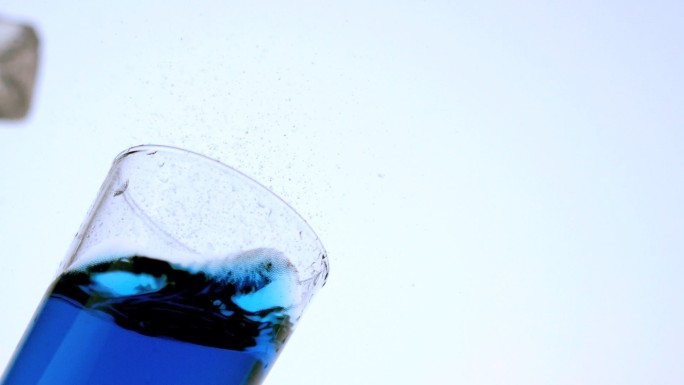 冰块掉入一杯蓝色液体中特写