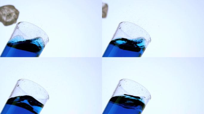 冰块掉入一杯蓝色液体中特写