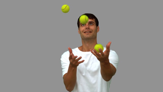 男人在灰色背景下拿着网球向上抛特写