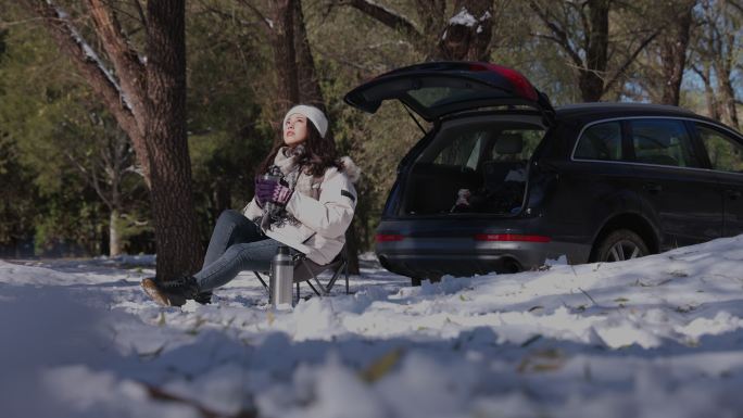 青年女人坐在雪地里喝热水