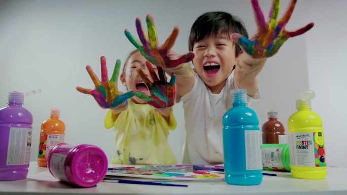 小男孩和小女孩用涂满颜料的手画画