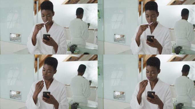 非洲裔美国美女在浴室刷牙和使用智能手机