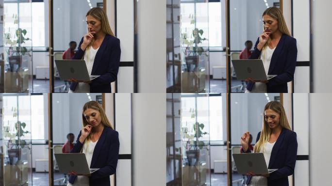 站在现代办公室里用笔记本电脑微笑的白人女性
