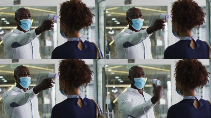 非裔美国商人戴着口罩给到办公室的女同事测体温
