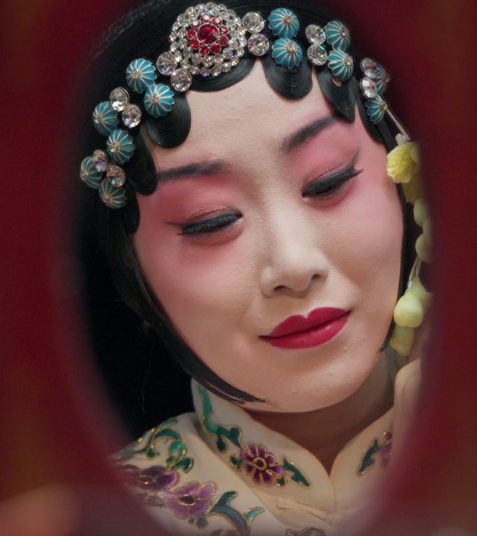 京剧女演员对着镜子整理妆容