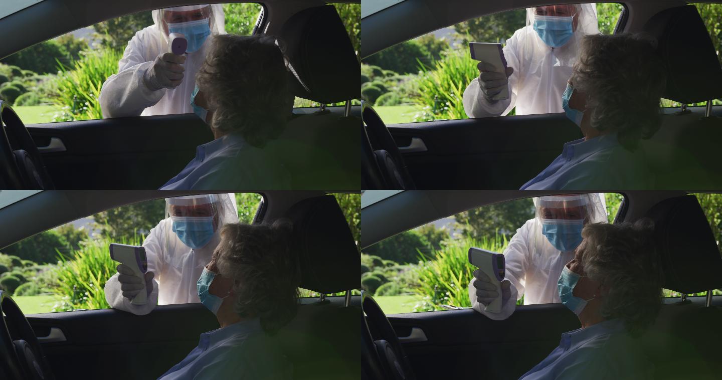戴着口罩坐在车里的白种高级妇女，由穿着防护服的男子测体温