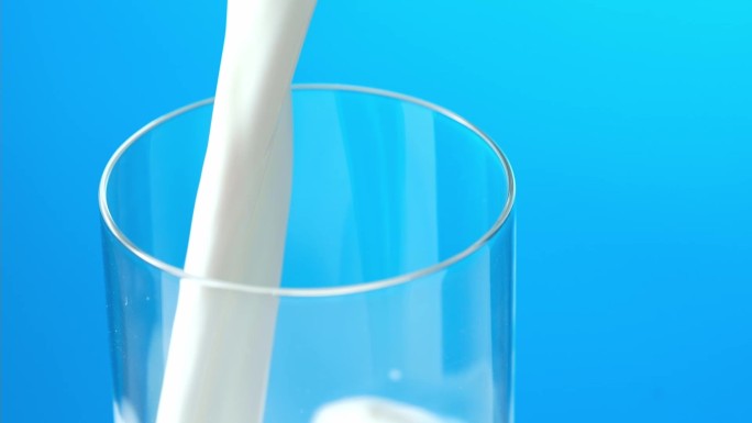 牛奶倒入玻璃杯中白色蓝色流动