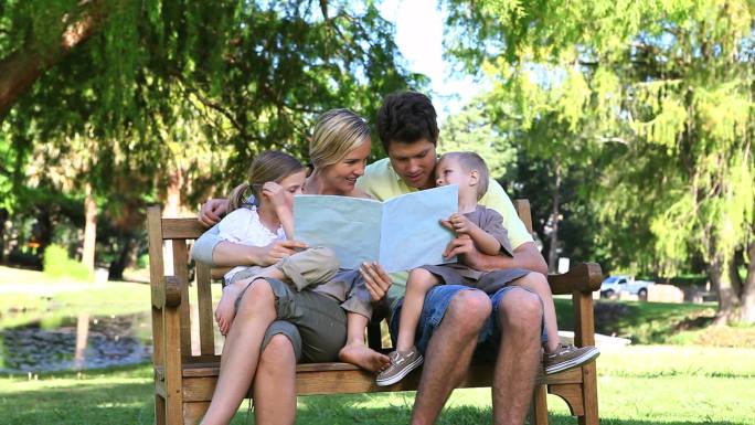 一个家庭坐在公园长椅上看书特写