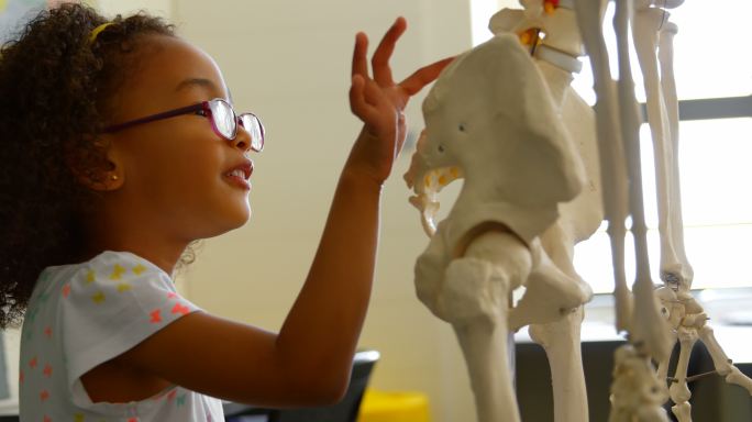 侧面的非洲裔美国女学生学习人体骨骼在教室在学校4k