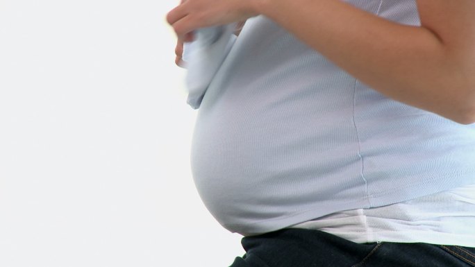 一个孕妇玩着婴儿鞋特写