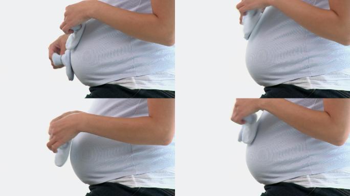 一个孕妇玩着婴儿鞋特写
