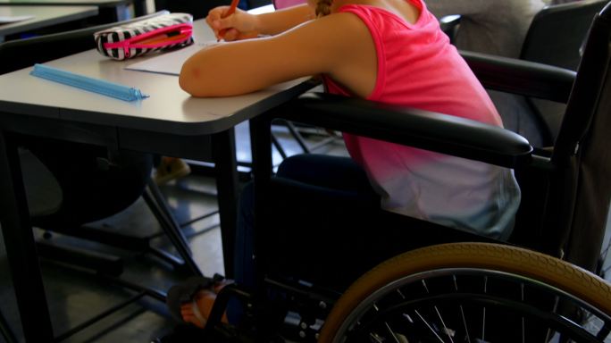 残疾白人女学生在课桌上学习在学校4k
