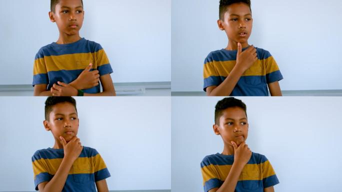 一个非洲裔美国男孩，手托着下巴，靠着白板站在4k教室里