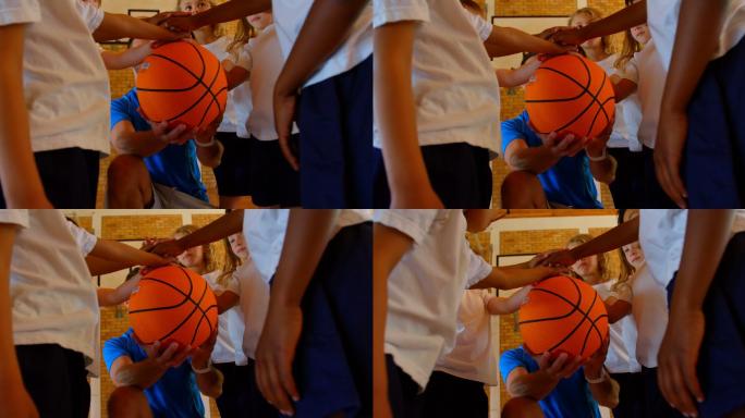 篮球教练和小学生组成4k手堆在篮球场上
