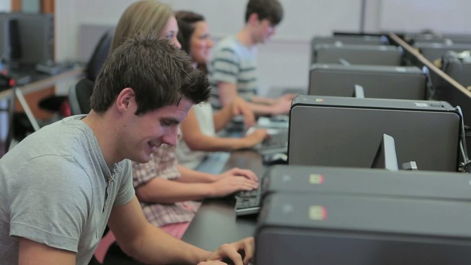 大学计算机课上的学生们，一个男人正对着镜头微笑