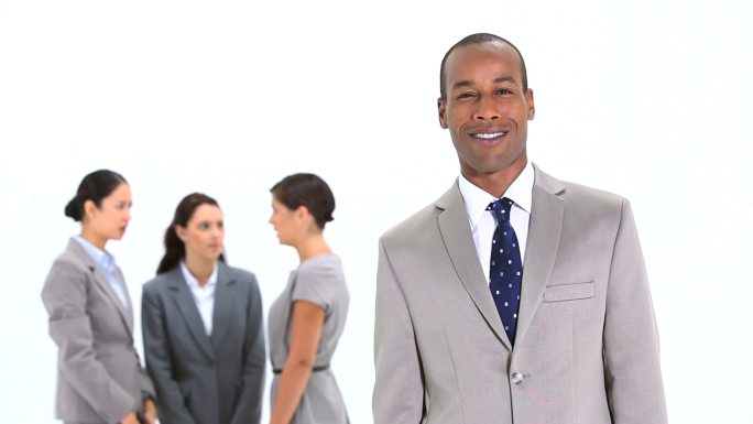 微笑的商人站在同事面前，背景是白色
