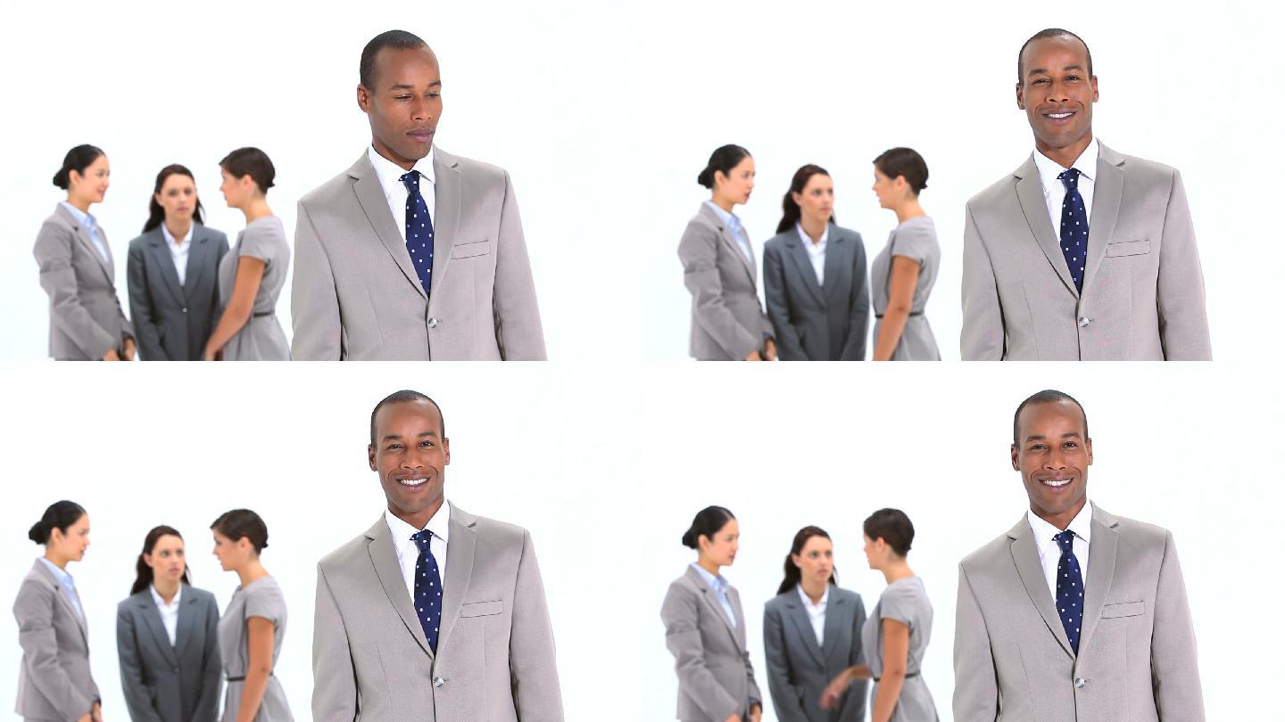 微笑的商人站在同事面前，背景是白色