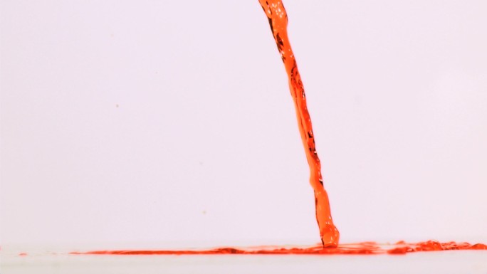 橙色液体以超慢的动作在白色背景下的地面上流动