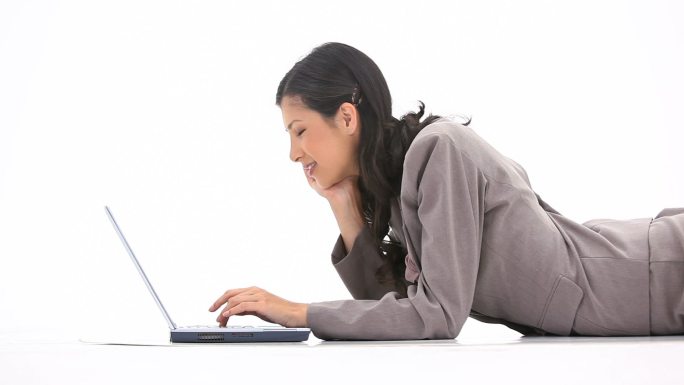 一段优雅女性俯卧使用笔记本电脑的视频