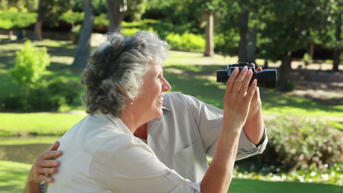 一对退休夫妇在乡下用望远镜看东西