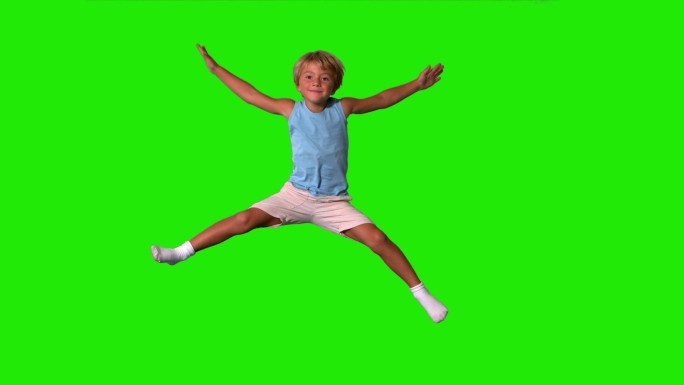 男孩在绿色屏幕上伸开四肢跳跃的慢动作