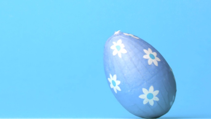蓝色包裹的复活节彩蛋滚动在蓝色背景的慢动作