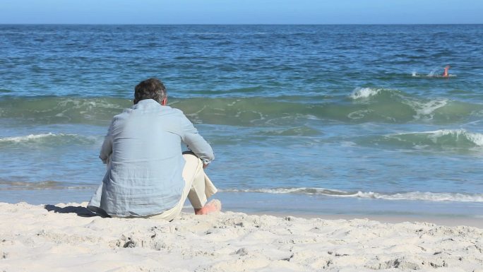 一个男人坐在海滩上特写