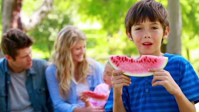 一个男孩和他的家人在公园里吃西瓜