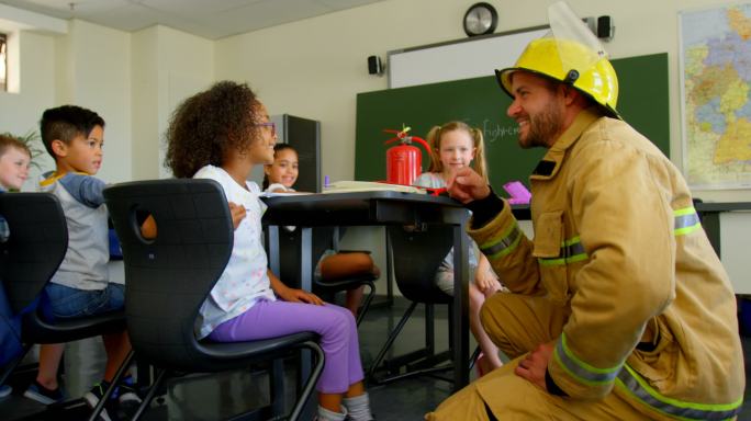 年轻英俊的白人男性消防员教女学生消防安全在教室4k