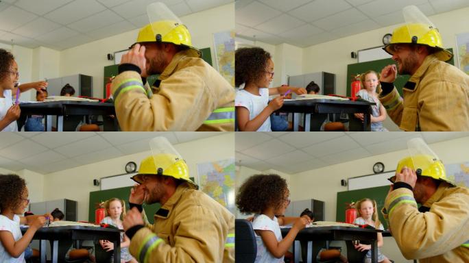 年轻的白人男性消防员教女学生关于消防安全在教室4k