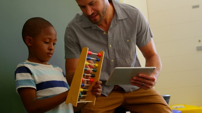 正面的年轻白人男老师教学生使用算盘在教室4k