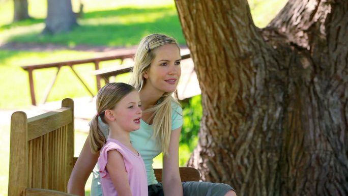 一个年轻女子和她的妹妹坐在公园的长椅上