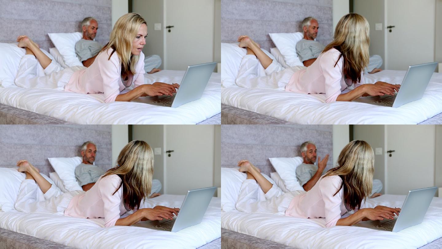 困惑的妻子一边看笔记本电脑一边问丈夫问题