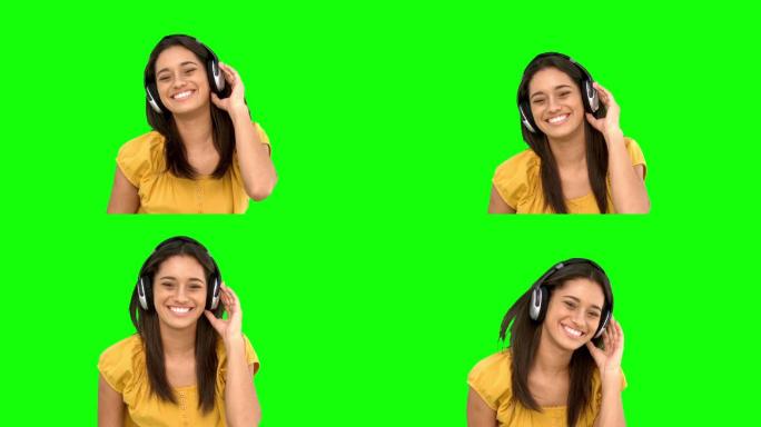 女人在绿色背景下戴着耳机听音乐特写