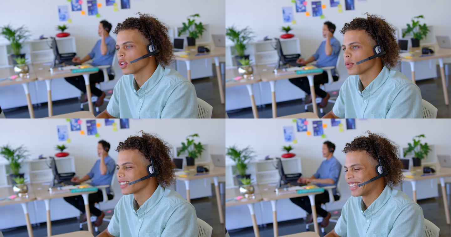 年轻的混血男性主管在4k办公桌前用耳机说话