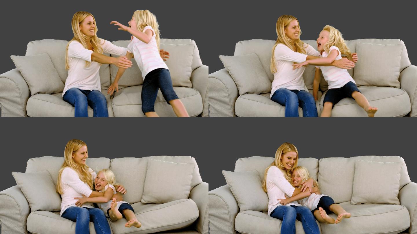 灰色背景下的慢镜头中，女儿在母亲的怀抱中跳跃