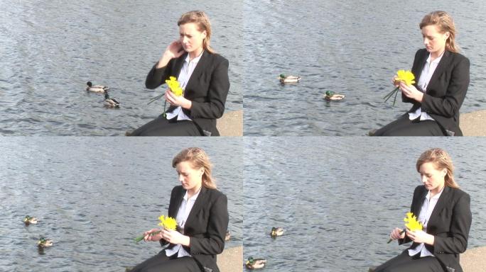 一个女人拿着花坐在河边特写
