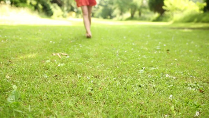 一个女人光着脚在草地上走特写