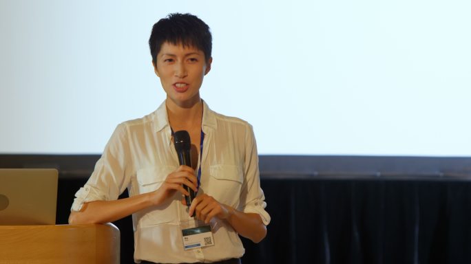 在4k大礼堂的舞台上，年轻的亚洲女商人在演讲