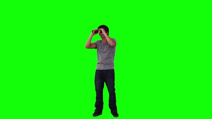 一个面带微笑的男人正在绿色背景下透过望远镜看东西