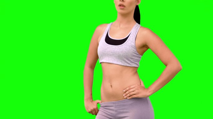 绿色屏幕下女人穿着运动服展示肌肉特写