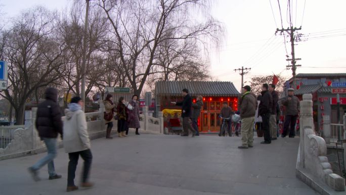 北京什刹海古桥行人们枯树