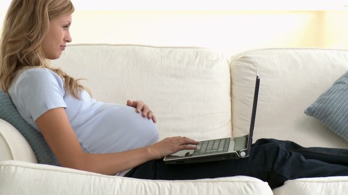 孕妇在沙发上看电脑特写