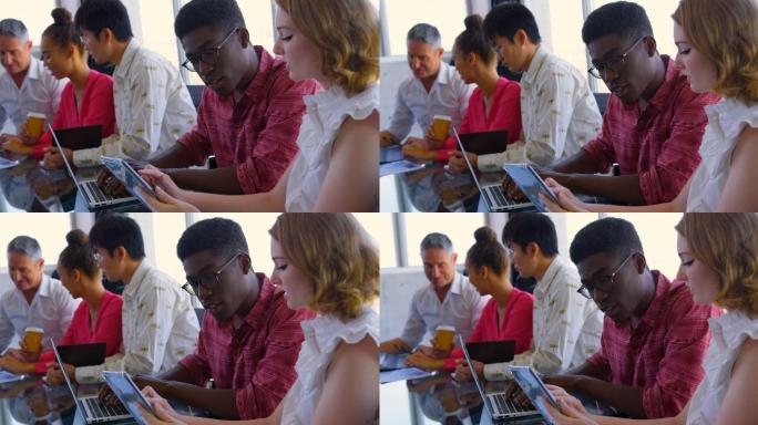 在现代办公环境中，来自不同种族的同事在数码平板电脑和笔记本电脑上讨论