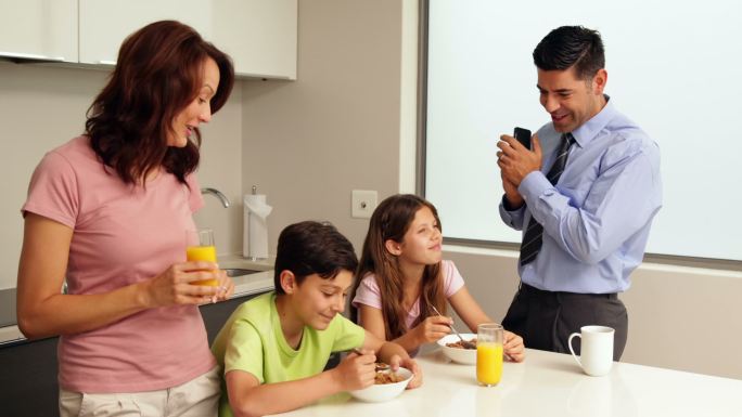 微笑的家人在早餐前，父亲去工作在家里的厨房