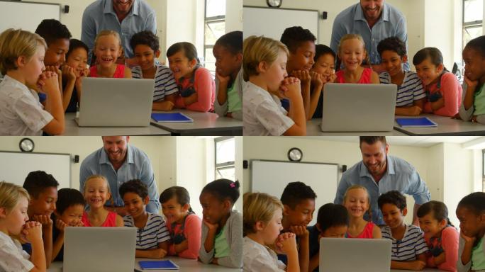 成年白人男性教师在教室里用笔记本电脑教孩子们