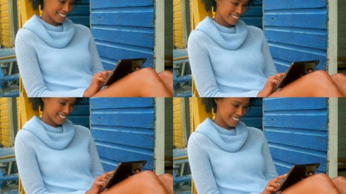 年轻的非洲裔美国妇女坐在沙滩小屋上使用数字平板电脑4k
