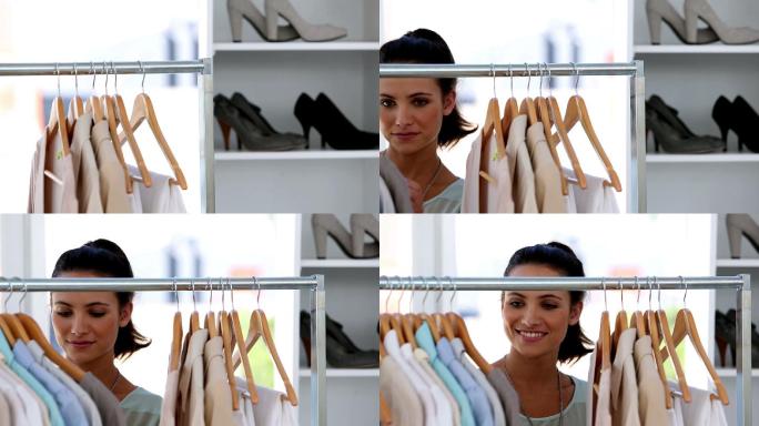 微笑的年轻女子在服装店选择衣服