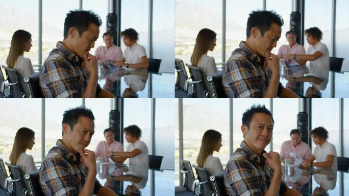 深思熟虑的年轻亚洲男性主管坐在会议室的桌子在4k办公室