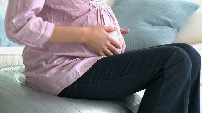 孕妇坐在沙发上摸肚子特写
